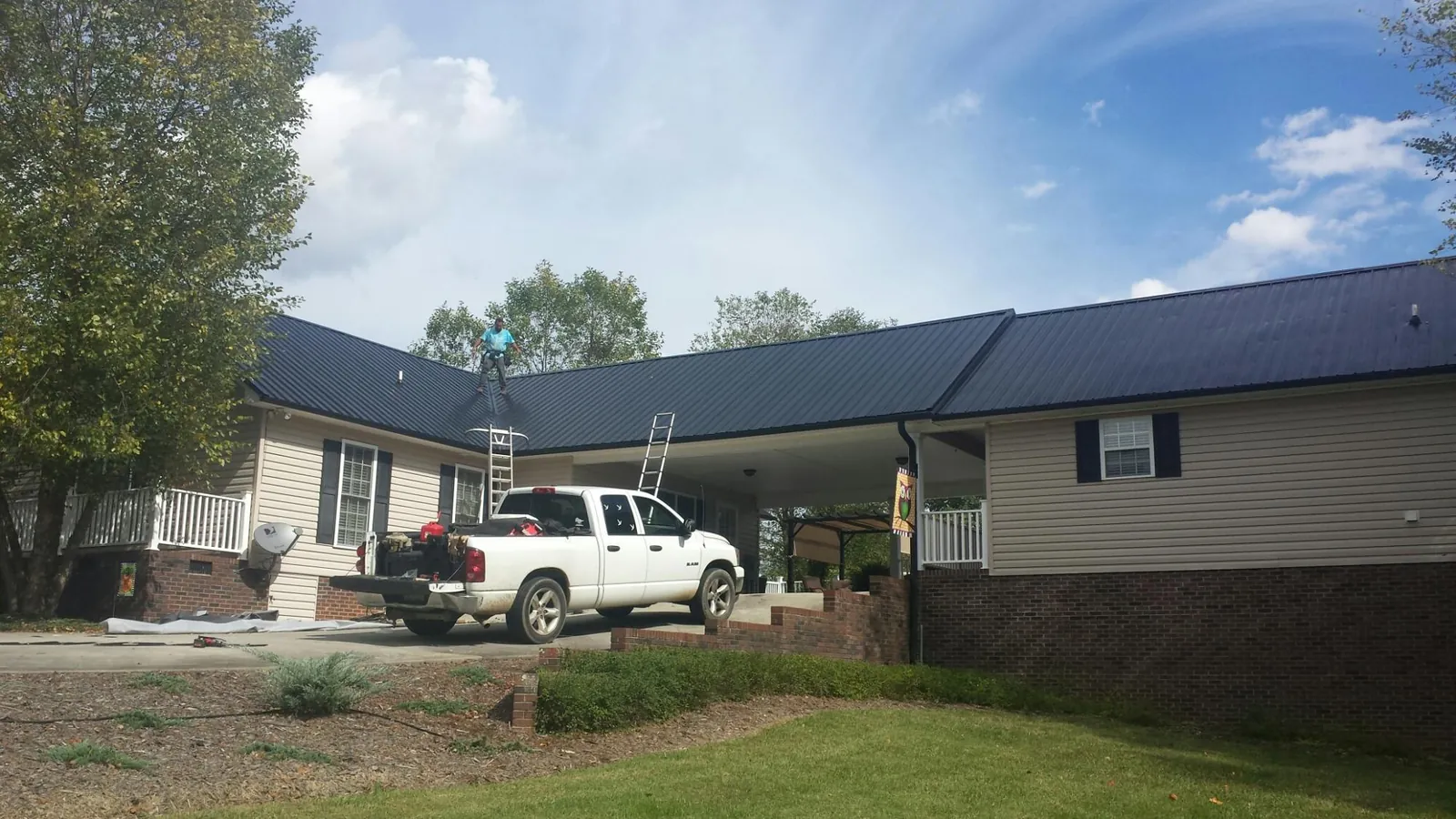 Black metal roof over a home and attached breezeway with ladders set in Stockton